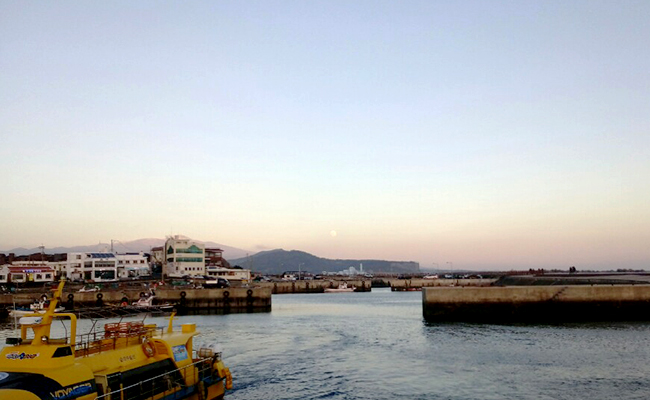 해상정류장으로 향하는 선박 뒤로 산방산이 보인다.